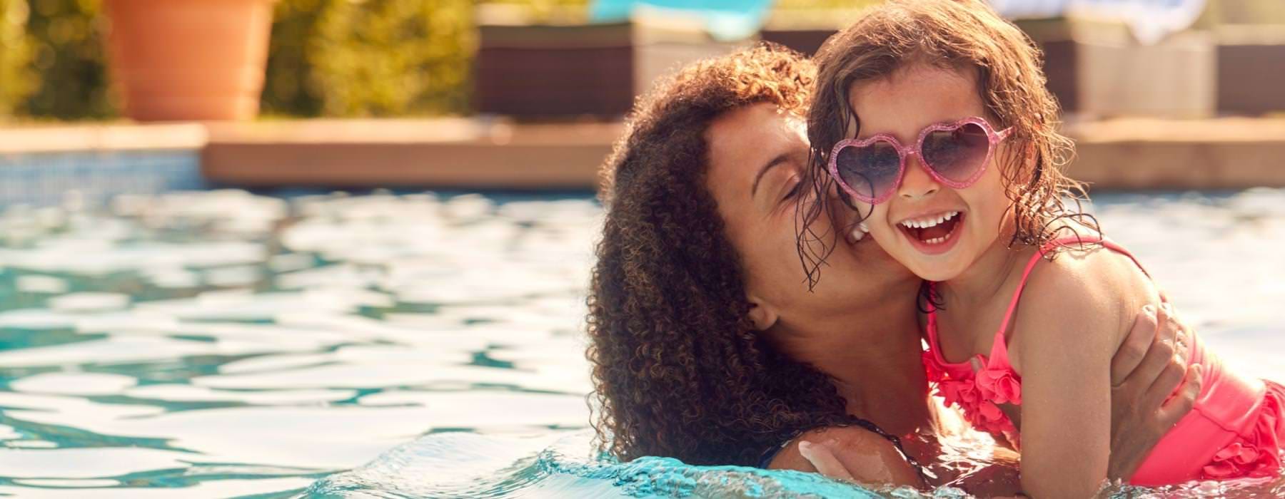 a woman hugging a girl in a pool